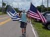 A demonstrator holds an American flag in one hand and a law enforcement flag in the other.