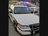The officer was injured by shattering glass when bullets hit the front and rear windshield of the cruiser. 