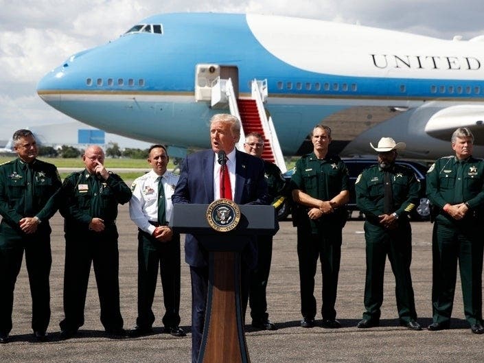 With Air Force One in the background, President Donald Trump speaks at Tampa International Airport during a campaign event with the Florida Sheriffs Association in Tampa Friday. 