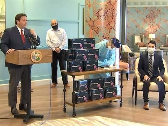 Florida Gov. Ron DeSantis enlists a staff member to demonstrate how fast the new BinaxNOW tests deliver results.