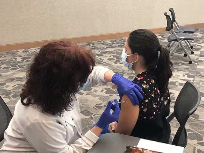 BayCare’s manager of employee health, Milissa Sulick, provides a coronavirus vaccination to registered nurse Deanna Myers.
