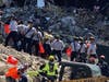 Searchers form a bucket brigade, moving away debris by the bucket. 