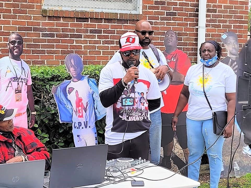 East Tampa residents stand next to life-size cardboard photos of their loved ones lost to gun violence. 