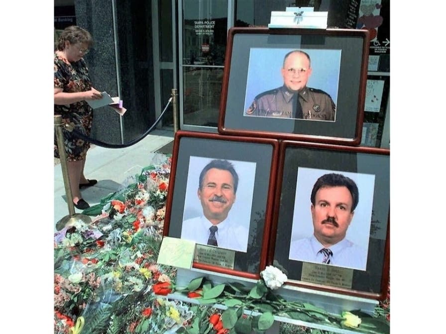 Residents place flowers around a memorial set up in front of Tampa Police Headquarters.