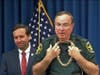 State Attorney Brian Haas chuckles as Polk County Sheriff Grady Judd models one of the gold necklaces confiscated during the investigation. 