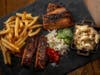 Mighty Quinn's BBQ offers a two- or three-meat platter with a choice of spare ribs, brisket, chicken, brontosaurus rib and sausage with a choice of sides.