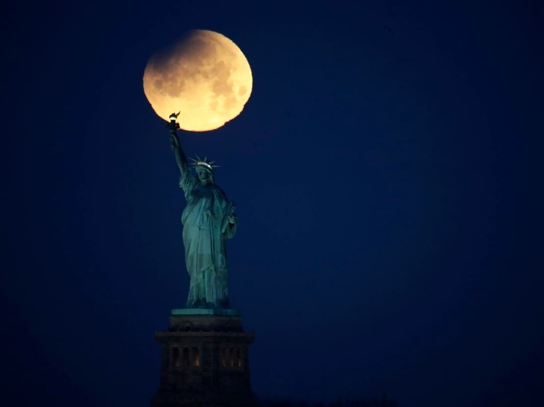 The Statue of Liberty appears to be hoisting a supermoon, a full moon that appears up to 30 percent brighter and 14 percent larger when it makes its closest approach to Earth in its elliptical orbit.