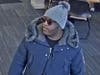 The suspect shown in the attached bank surveillance photos is described as a black male wearing a dark colored hooded winter jacket, a gray winter cap, and sunglasses, according to police.