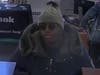 The suspect shown in the attached bank surveillance photos is described as a black male wearing a dark colored hooded winter jacket, a gray winter cap, and sunglasses, according to police.