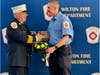 Wilton Deputy Fire Chief John Plofkin Jr. presenting Timothy LeStrange with his fire helmet