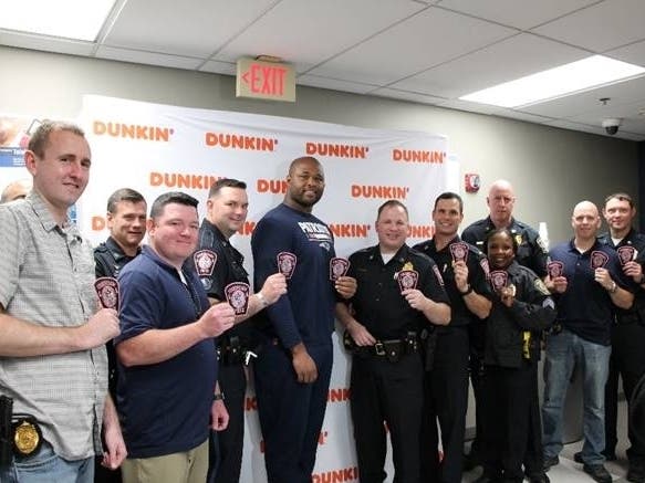 Patriots offensive lineman Marcus Cannon, Police Chief Michael Grace and several officers from the Foxborough Police Station hold up pink Foxborough Police patches as part of the Pink Patch Project.