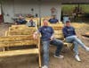 Volunteers take a break on a few of the benches they built for campers.
