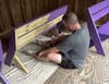 Hugh Howard, now manager of the Elm Street branch of St. Mary’s Bank in Manchester, paints a bench at Camp Seawood.