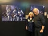 Leslie Bean with Mike Massimino in front of Alan Bean's painting reprints. 