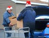 Santa Ken's loading two Christmas Baskets into a recipient's vehicle