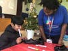 A Wesley Elementary student decorates his new shoes with help from CIS of Houston
