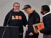 Leo High School president Dan McGrath surprises World War II veteran Jim Wilkins of Orland Park with his Leo Hall of Fame plaque during Thursday’s Veterans Day Ceremony at the school, where administrators moved the ceremony inside. Wilkins is 95.