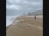 Vacationer Kelley Motts braves the storm to take video on beach.