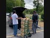 Church members putting box vegetables inside cars to help people in the community.