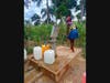 A young girls uses the water pump in Haiti.
