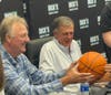 Celtics Legends Larry Bird and Kevin McHale sign a basketball for a fan.