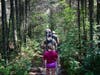 A group of Girl Scouts and their families walk through a shaded trail at Double Trouble State Park.