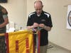 Special Agent Eric Woodard placing the streamer on the unit guidon that accompanies the plaque