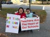 Young Chase Parnell holds a picket sign alongside his first grade teacher outside Greenlodge Elementary in Dedham.