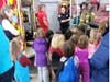 Acton firefighter Jared Crowley explains how a folding pencil ladder works to the group of young visitors on Friday.
