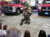 Firefighter Steve DiMeco demonstrates how to put on all the gear a firefighter wears to children from the Infant Toddler Children Center.