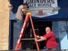 Jared Harms helps owner John Macrito (right) put up a new Grinders Ale House sign along Pearl Street in McHenry this spring. The business went from re-branded last summer to believed sold in the fall, then started over from scratch this year.