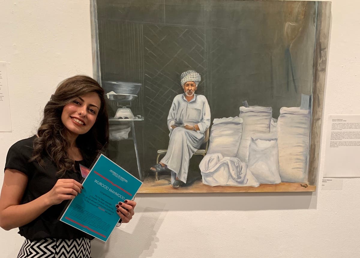 Wurood Mahmood of New Haven stands next to one of her portraits at the Donald and Linda Silpe Gallery in West Hartford. 