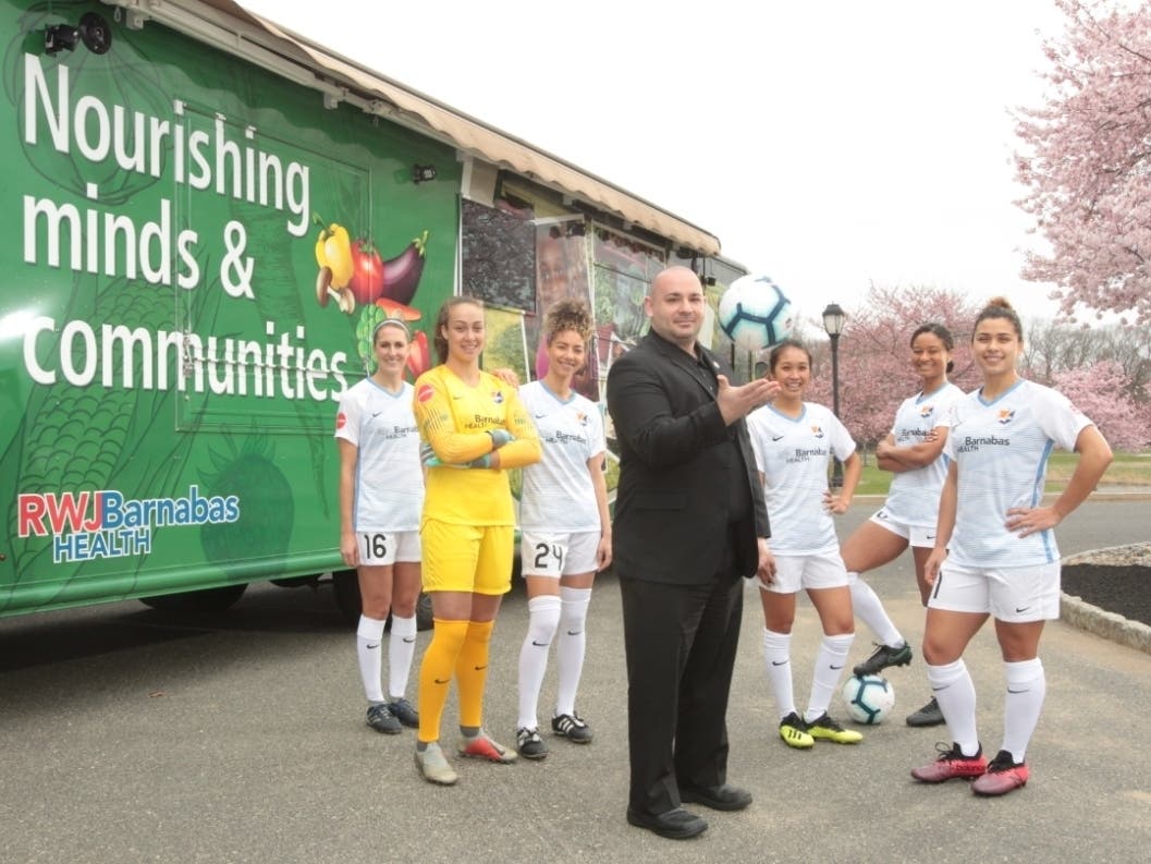 Jason Krystofiak, MD stands with Sky Blue FC players.