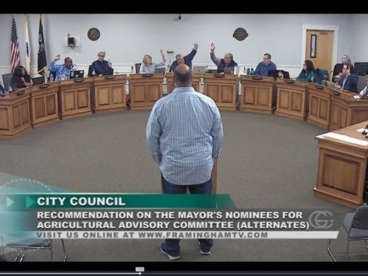 Kapust stands at the podium of the Framingham City Council while Councilors Ottaviani, Leombruno, King, Cannon, Alexander, Stefanini raise their hands to vote in favor of confirming his appointment to the Agricultural Advisory Board,
