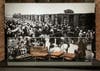 Suitcases confiscated from deportees to Auschwitz with a photograph of hostages arriving in the background.