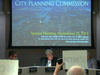Protesters hold signs at a review session by the City Planning Commission.