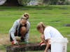 Community youth participate by removing dirt, and debris, from graves