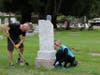 Overgrown grass is trimmed and headstones uncovered