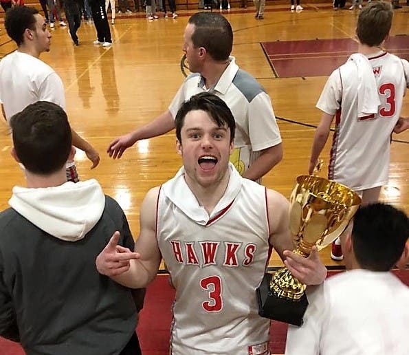 Waltham High School's Evan Clark celebrates with a trophy during a triumph this winter.