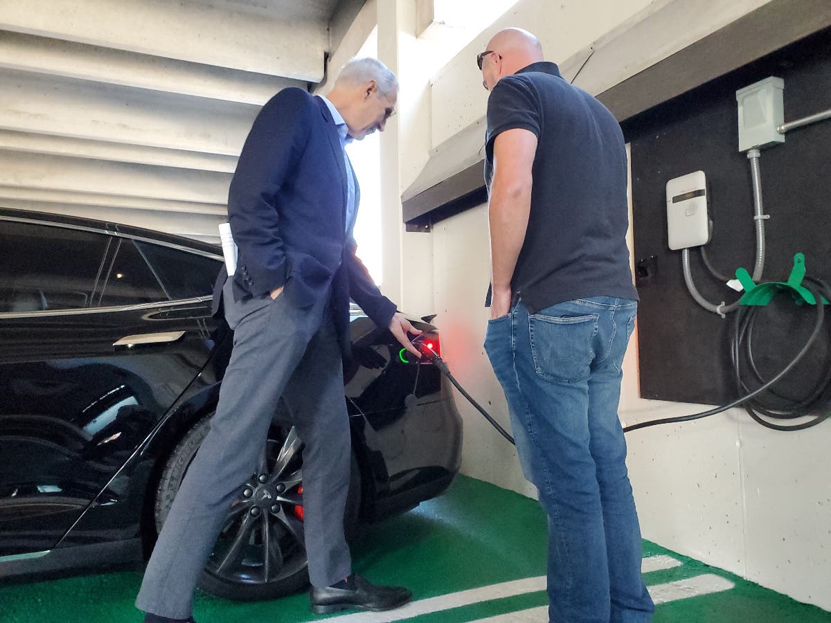 Nashua resident Ian Van Tassell charges his car in one of the city's new electric car charging stations, while talking with Nashua Mayor Jim Donchess, on Thursday..