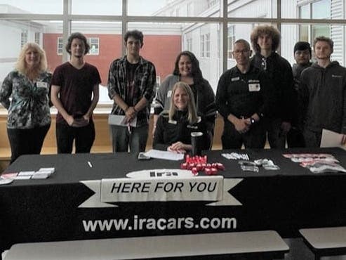 Charlene Snow, seated, from the MassHire North Shore Career Center, with IRA Automotive Group participating in an employer meet and greet for NightHawks Automotive Technician students.