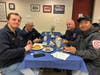 Woodbury Fire Captain Corey Shaker checks cell phone for emergencies at the department’s Valentines pancake breakfast for townsfolk on Feb 15th. Opposite, back right, Southbury Fire Chief Bob Hamila. Two Southbury fire lieutenants are at front.