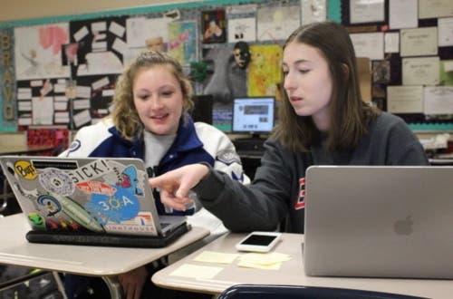 Alyssa Freyman, right, helps a fellow student with designing an image on Photoshop.