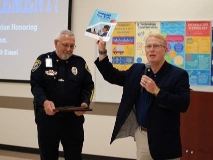 Superintendent Brian Hightower, right, gives Police Chief Mark Kissel a parting gift for his retirement.