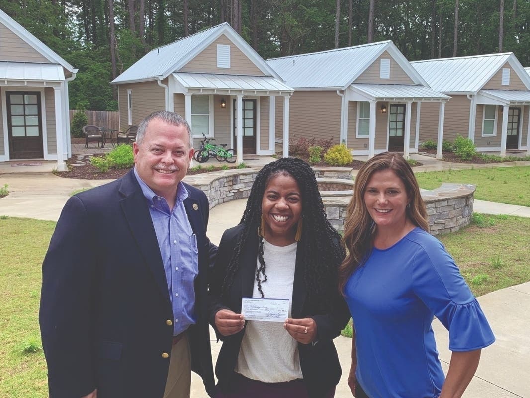 Rotary Club of Canton President Stacey D. Williams, left, and Rotarian Shannon Wallace, who serves as Cherokee County’s District Attorney, right, present a $1,000 donation to Wellspring Tiny House Village Coordinator Najma Calhoun.