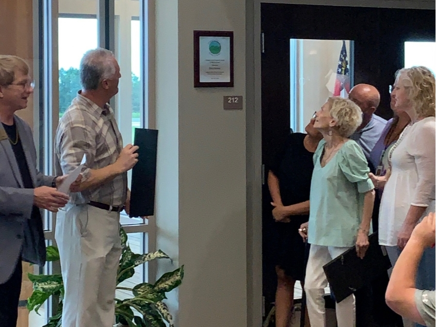 Don Stevens' widow, Lila Stevens, right, witnesses the unveiling of the newly renamed conference room in Don’s honor.