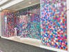 With bold colors and a message of positivity, “Gumballs” features large jumping dots – some glittered to evoke movement – that brighten and transform the otherwise blank storefront.