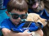 Ian Farmer cuddles with future autism service dog Peaches at BluePath Service Dogs’ sixth annual walkathon. 