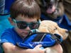 Ian Farmer cuddles with future autism service dog Peaches at BluePath Service Dogs’ sixth annual walkathon