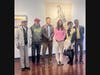 Pearl Shen takes a photo with guests in front of her artwork.